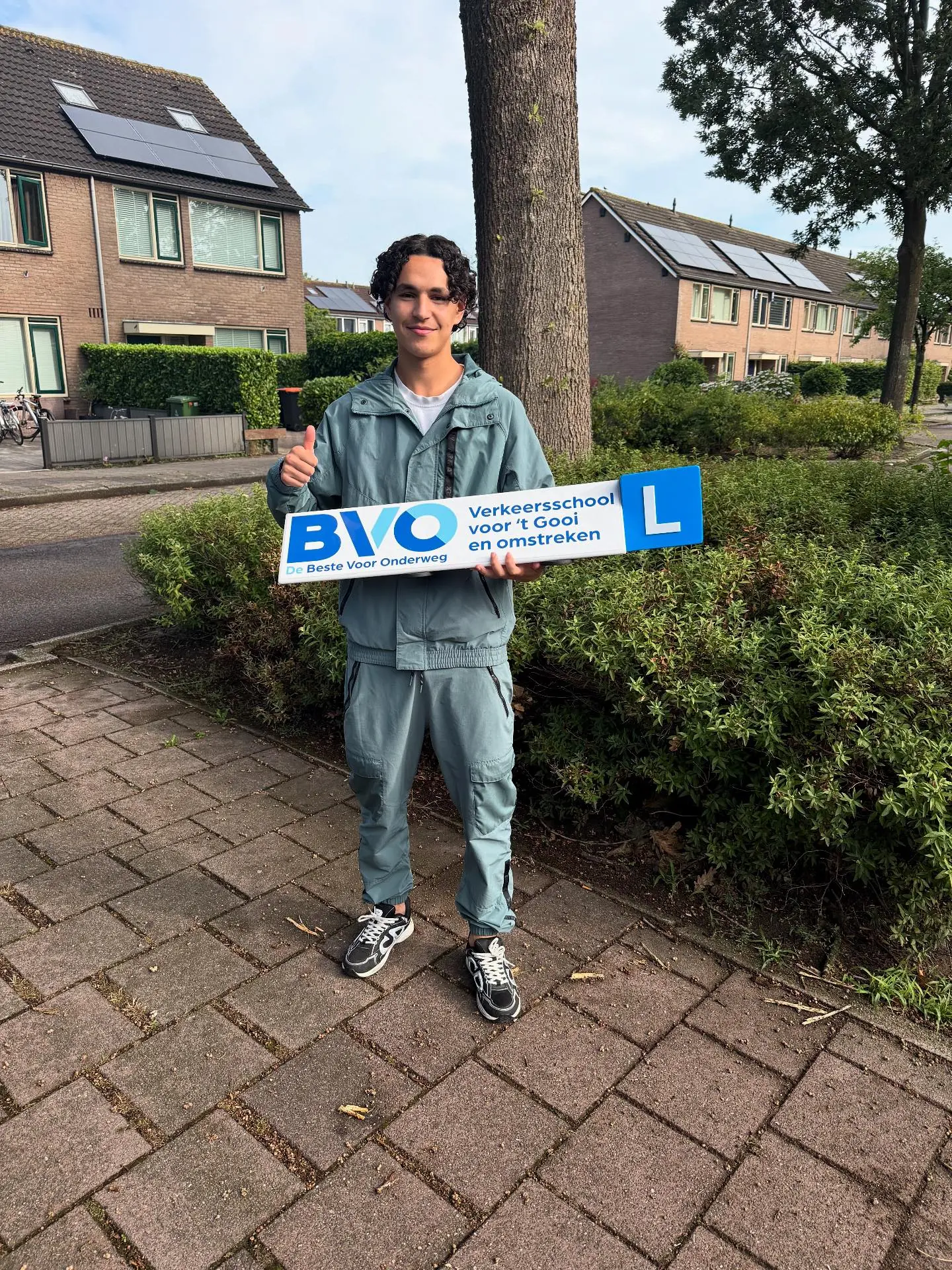 Geslaagde leerling van Rijschool BVO met het bord van BVO, De Beste Voor Onderweg